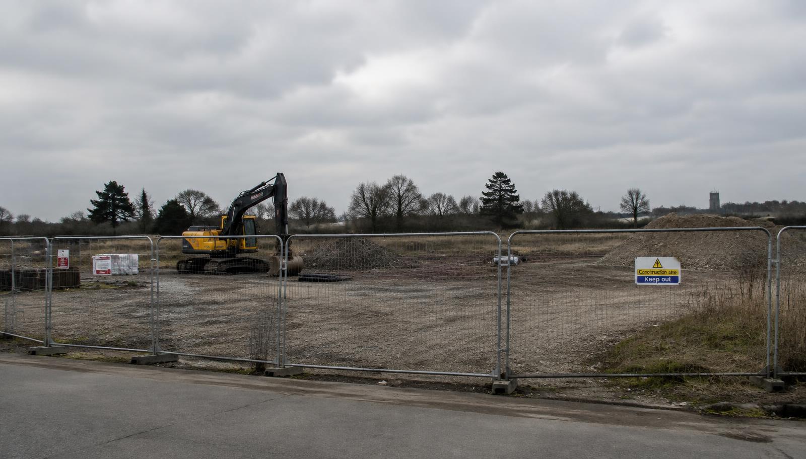 Construction site fenced off with a halted excavator